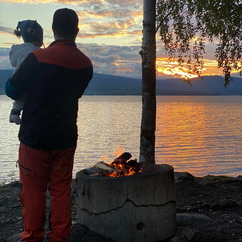 Voksne og barn med utsikt over hurdalsjøen ved siden av bålet